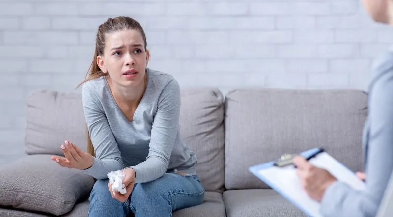 Young woman in counseling discussing talk therapy vs psychotherapy during a private session.