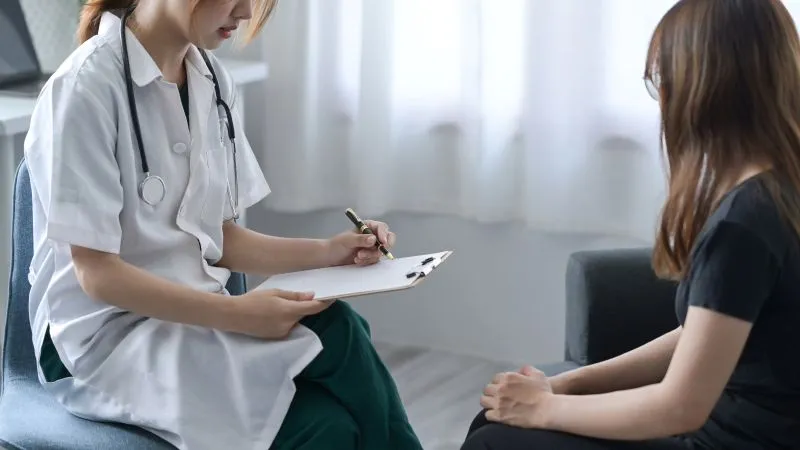 Psychiatrist conducting a therapy session, focusing on the patient with antisocial personality disorder treatments, recording notes during a consultation.