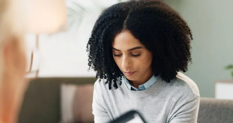 Woman attending a mental health appointment, engaged in a thoughtful discussion with a professional