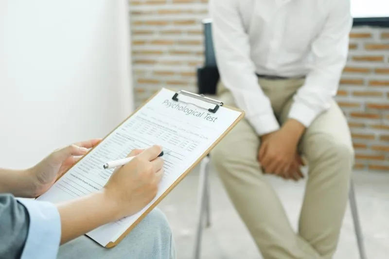 A psychotherapist in Brooklyn NY takes notes while administering a psychological test to a patient, focusing on mental health assessments and therapy progress.
