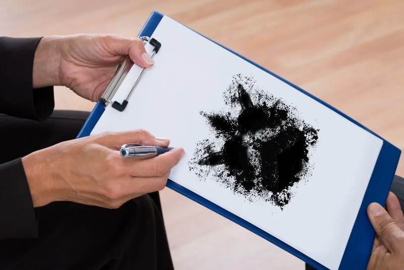 A mental health and psychiatric nursing professional administering a Rorschach inkblot test as part of a patient assessment in a therapeutic setting.