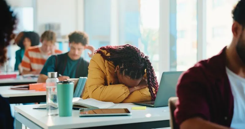A student experiencing fatigue or overwhelm in class, possibly struggling with focus and attention, which could be supported through ADHD therapy.