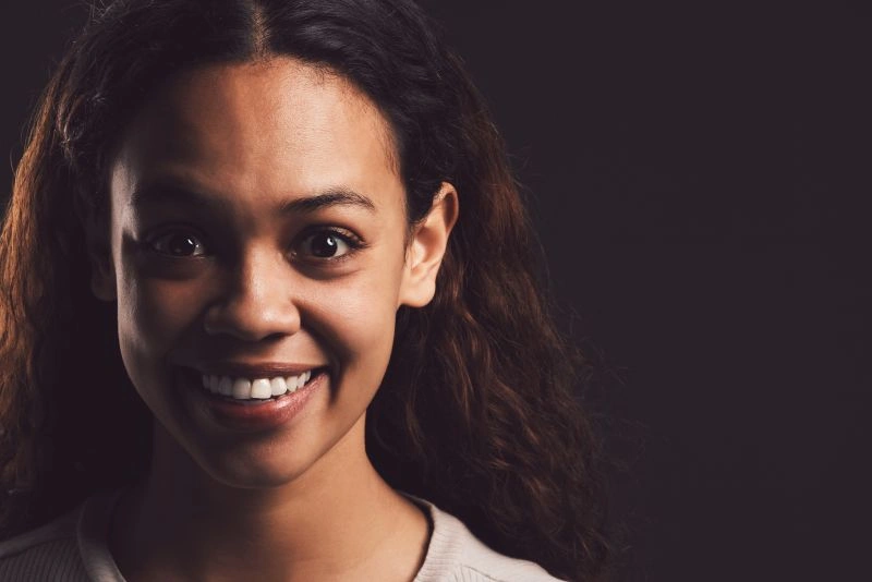 A woman smiling with wide eyes in a close-up shot, reflecting the contrast of emotions that can be experienced by those with schizoaffective disorder, where both elevated moods and depressive states may occur alongside psychotic symptoms.