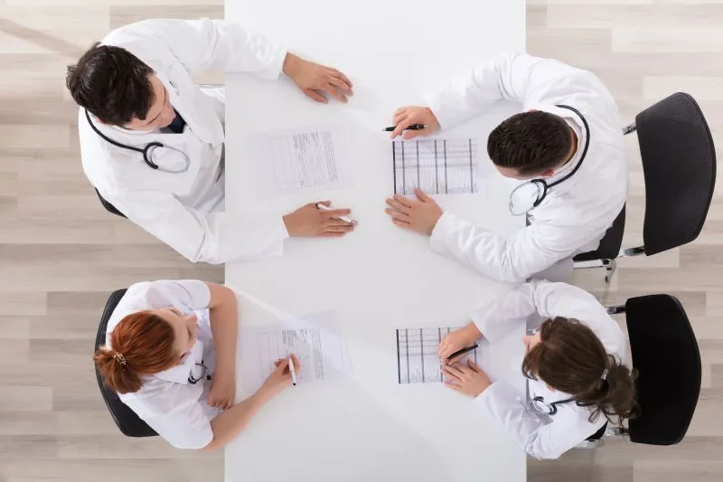 A team of doctors discussing medical documents in a professional setting. This image emphasizes the collaborative nature of integrated psychiatric services, where multiple specialists work together to provide comprehensive care.