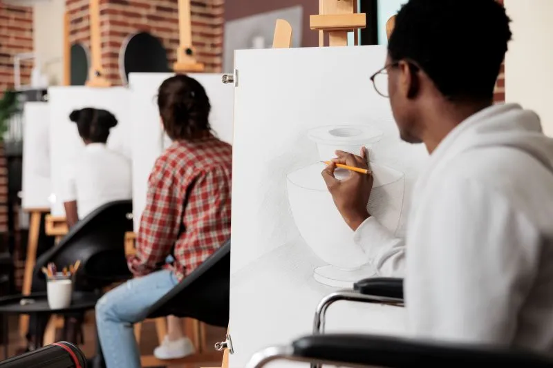 People participating in an art class, focusing on sketching still-life objects. This activity exemplifies how expressive arts therapy can help individuals explore emotions and self-expression through creative outlets