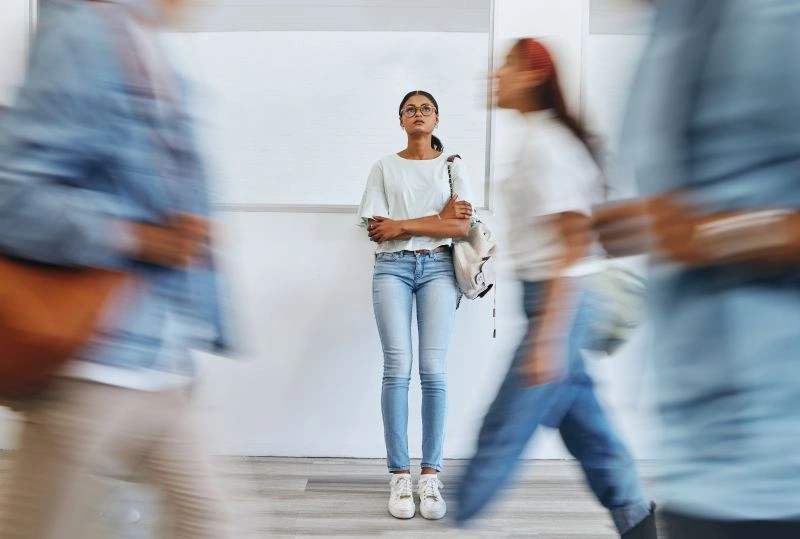 A young woman standing still in a busy environment, appearing overwhelmed and isolated. This image represents how individuals with borderline personality disorder may experience emotional distress, highlighting the importance of new treatments to manage these feelings.