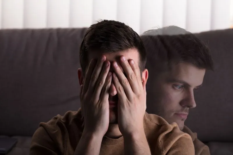A man covering his face with his hands in distress, representing the emotional burden of unresolved childhood trauma and the process of seeking healing and recovery.
