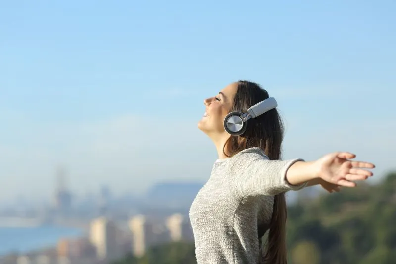 A woman enjoying music outdoors with headphones, reflecting the emotional well-being that can be impacted by untreated ADHD, potentially leading to depression and anxiety.