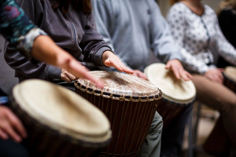 A group of people participating in a drumming activity, illustrating the therapeutic approach for managing untreated ADHD, which may help alleviate related depression and anxiety.