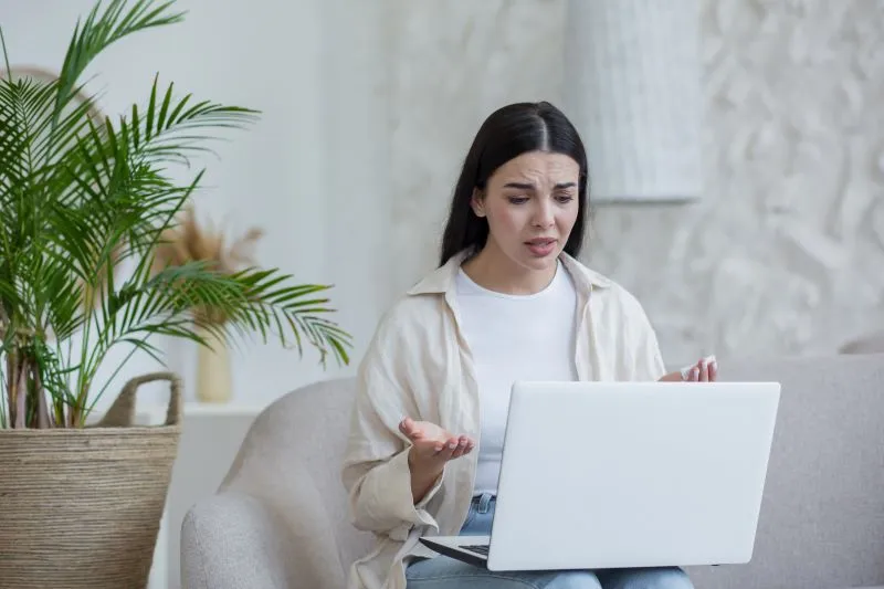 Teletherapy session: A woman expressing concern while engaging in a virtual therapy session on her laptop