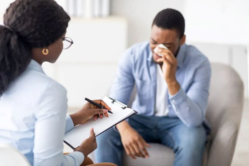 A man seeking therapy for emotional distress, discussing mood disorder vs personality disorder with a mental health professional.