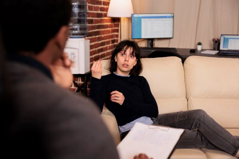 Teletherapy vs in-person: A woman engaged in a face-to-face therapy session, discussing her emotions and thoughts with a therapist.