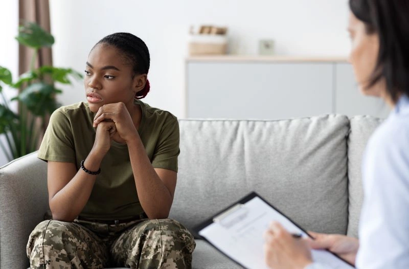 A female soldier sitting in a therapy session with an army mental health specialist, showcasing the importance of mental health support for military personnel.