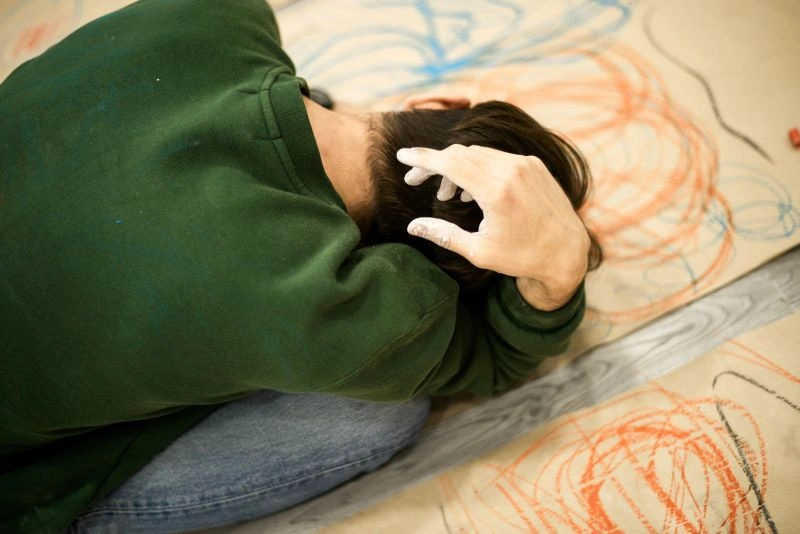 An individual with their head in their hands, expressing distress, which represents how cognitive therapy helps individuals address and transform negative thought patterns.
