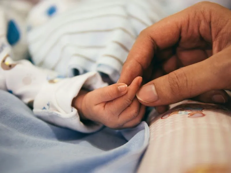 An infant mental health specialist holding an infant's hand, providing care and reassurance in a nurturing environment.