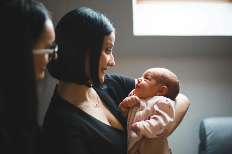 An infant mental health specialist interacting with a mother and her newborn, fostering a strong emotional connection and bonding during early life stages.