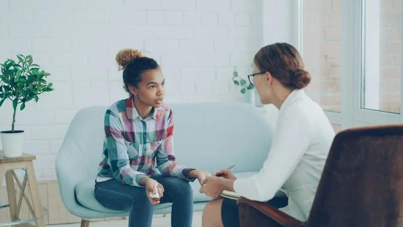 A peer support specialist offering assistance to a young individual during a one-on-one therapy session, fostering emotional well-being.