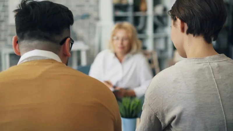 A peer support specialist interacting with a couple during a counseling session, providing guidance and support.