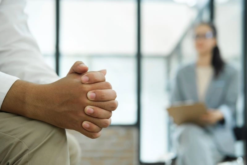 A close-up of an individual’s hands folded in a rehab session, symbolizing the process of reflection and recovery guided by a rehab specialist
