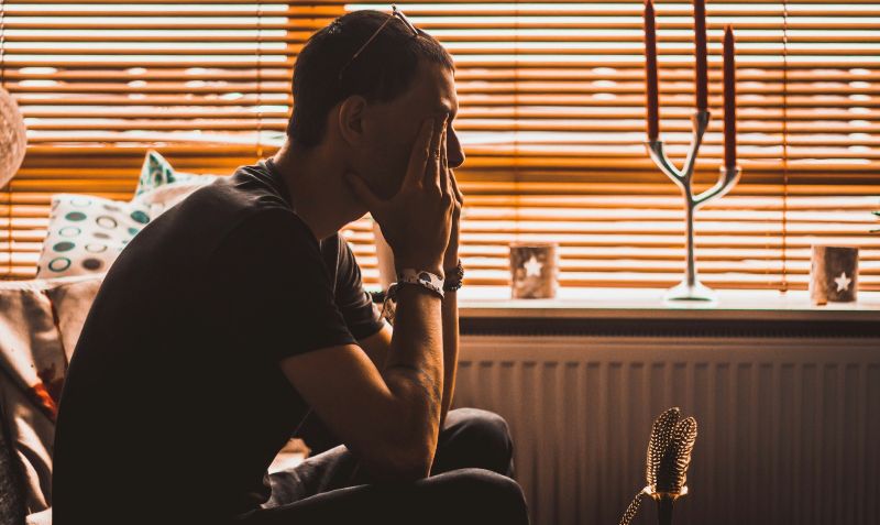 close-up of two people sitting at a table holding mugs, suggesting a quiet, emotionally restrained interaction in an interpersonal context.