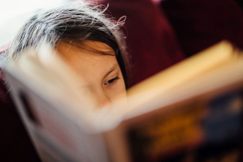child reading a book closely, focusing on personal growth and mindfulness for mental health self help
