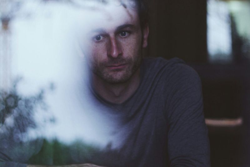 Thoughtful man looking out a window during burnout recovery and emotional healing.