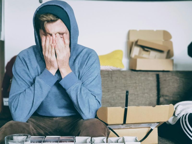 Overwhelmed person sitting with hands over face, representing the challenges of burnout recovery.