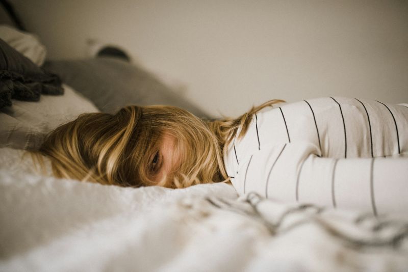 Tired person lying in bed, highlighting rest as an essential part of burnout recovery.