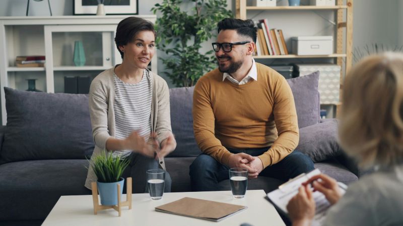 Couples therapy for communication issues with a couple speaking to a therapist in a supportive session focused on improving understanding and connection