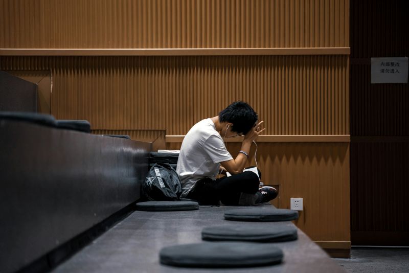 Student sitting alone with his head in his hands, illustrating emotional numbness in anhedonia vs depression.