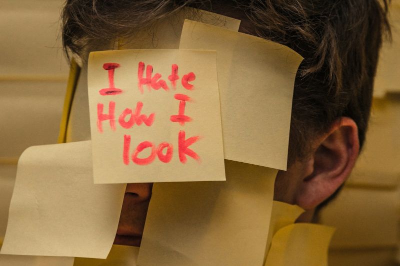 Person with sticky notes on their face expressing negative self-image associated with anhedonia vs depression.