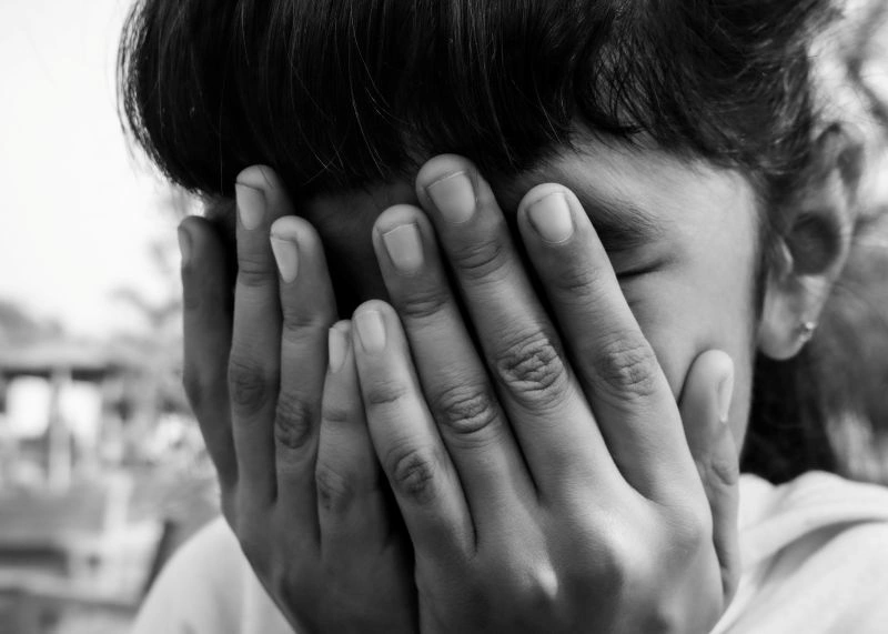 Person covering their face with hands, depicting emotional blunting and a sense of emotional disconnection.