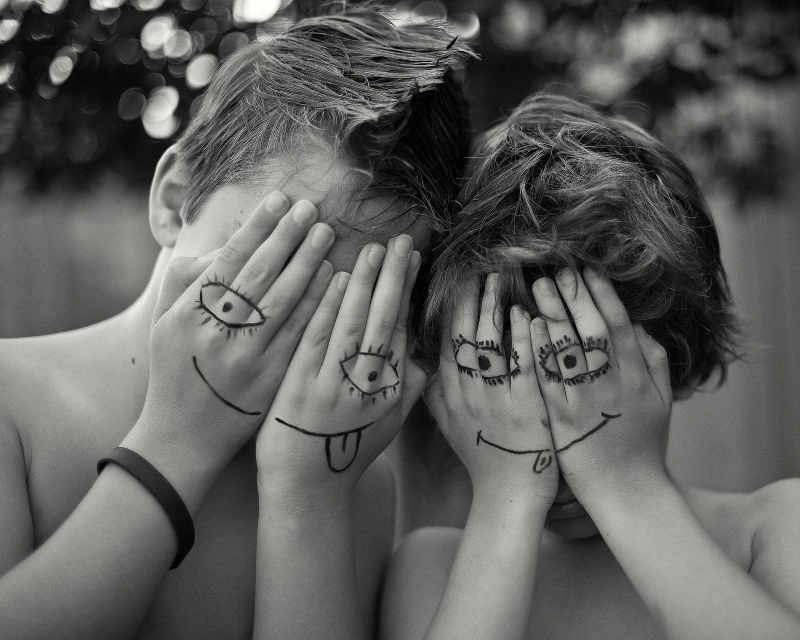 Two people covering their faces with drawn expressions, illustrating emotional blunting and hidden emotions.