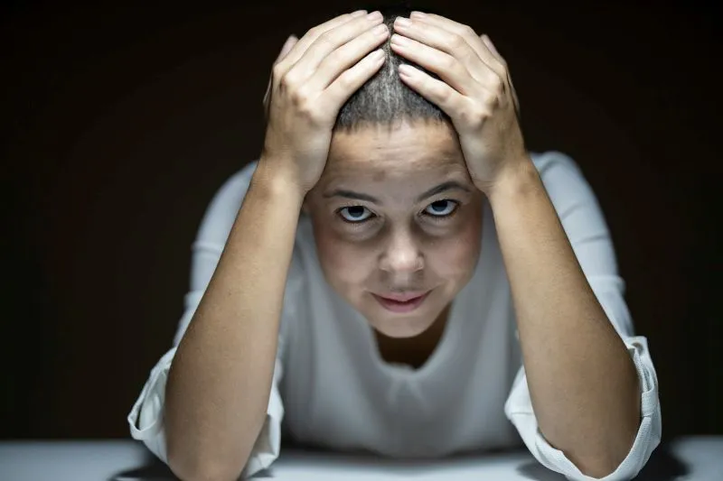 Stressed person holding their head while experiencing symptoms linked to major depression vs persistent depressive disorder.