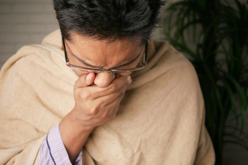Person feeling overwhelmed and covering their mouth, depicting emotional challenges linked to major depression vs persistent depressive disorder.
