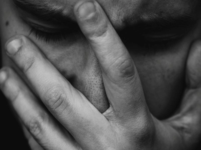 Close-up of a person hiding their face with hands, showing signs of emotional numbness and inner struggle.