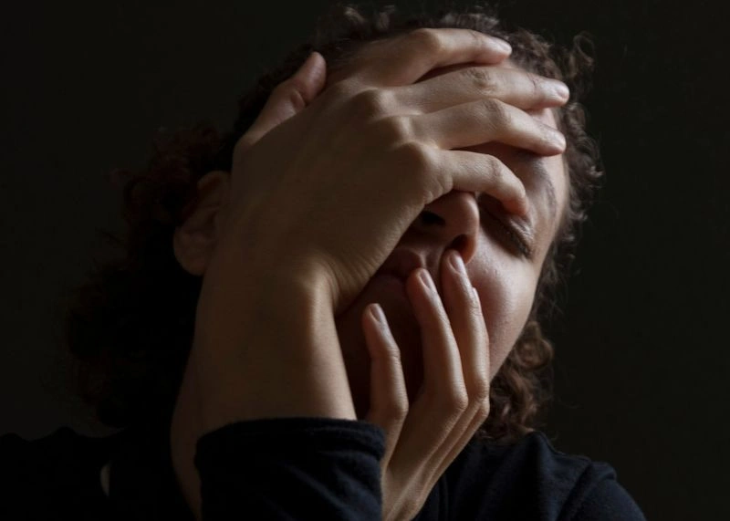 Person covering their face with hands, representing feelings of emotional numbness and emotional disconnection.