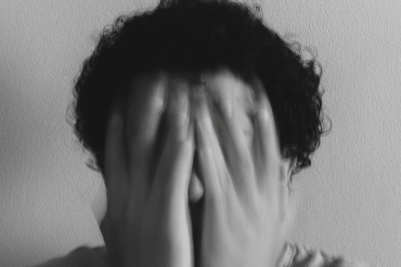 Person covering their face while feeling overwhelmed, depicting emotional distress linked to panic attack vs anxiety attack.