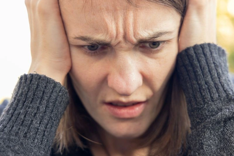 Close-up of a person holding their head with a worried expression, showing signs associated with panic attack vs anxiety attack.