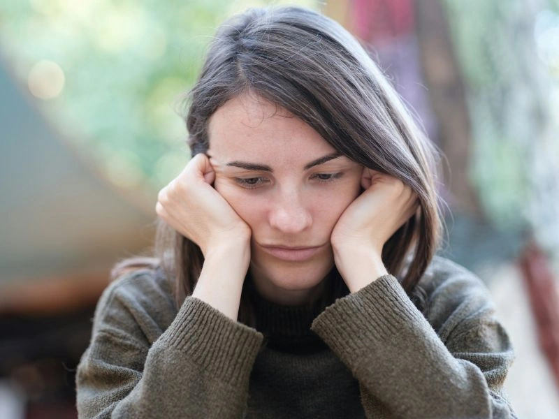 Person resting their head in their hands with a sad expression, representing emotional challenges associated with seasonal affective disorder bipolar.