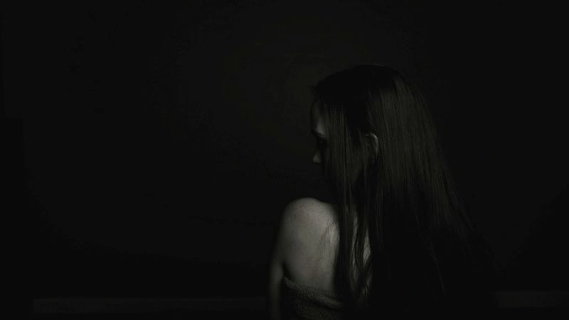 Person sitting alone in darkness while struggling with relationship OCD and overwhelming relationship worries