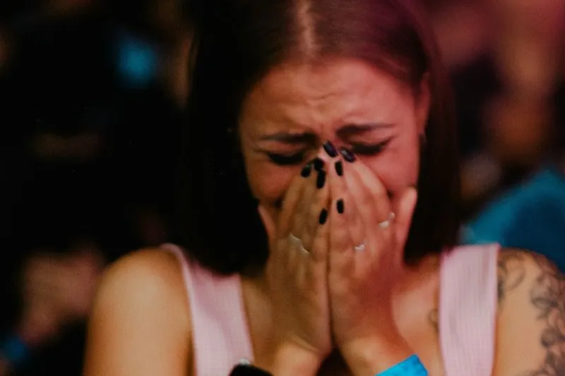 Emotional volatility shown by an emotional woman covering her face while crying.