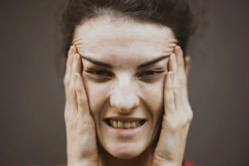Emotional volatility illustrated by a close-up of a tense person holding their face with both hands.