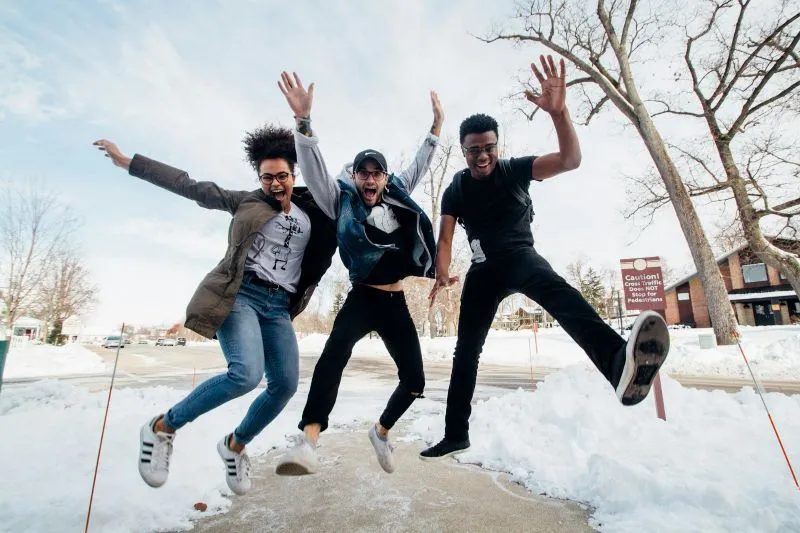 Hypomania vs mania shown through three friends jumping excitedly outdoors with high energy.