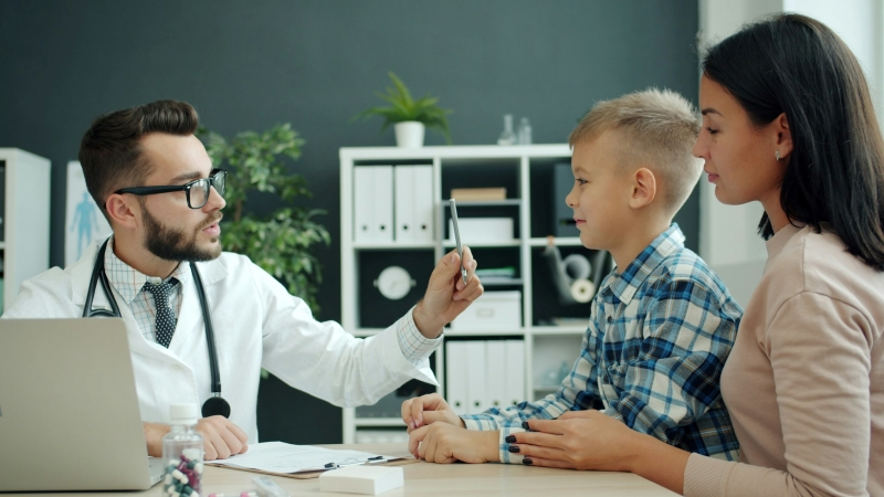 Pediatric specialist assessing a young boy while his mother learns how long does ADHD diagnosis take in children.