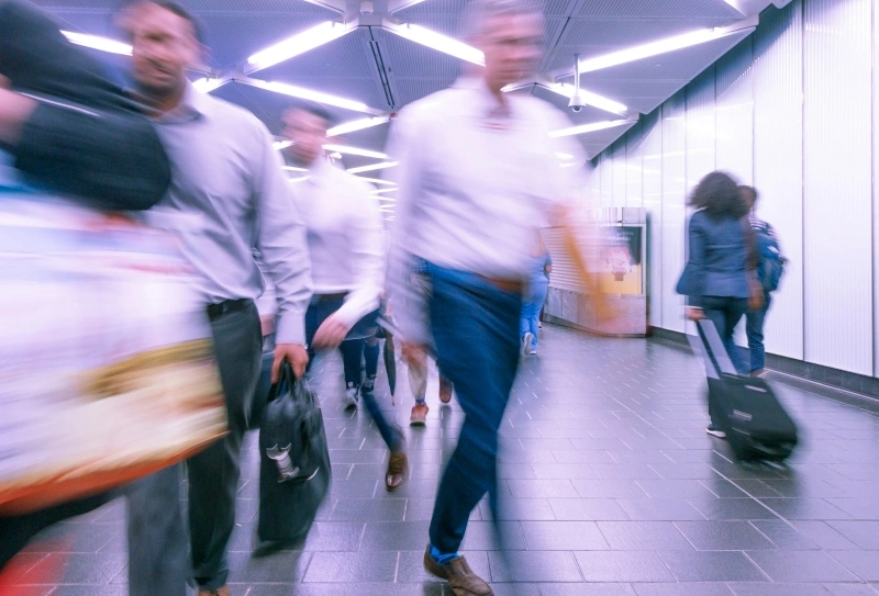 Motion-blurred commuters walking through a crowded station, representing ADHD and time blindness in everyday routines.