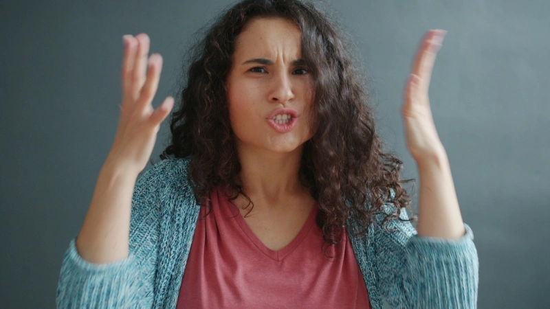 Frustrated woman raising her hands while speaking angrily, illustrating emotional stress and the question why am I so irritable.