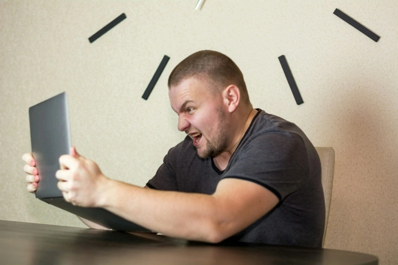 Frustrated man shouting at his laptop, illustrating stress, anger, and the common concern of why am I so irritable.